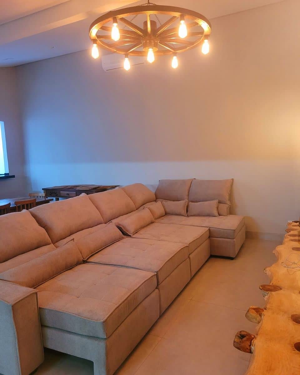 Sofá de canto em L bege em sala com lustre de roda de carroça